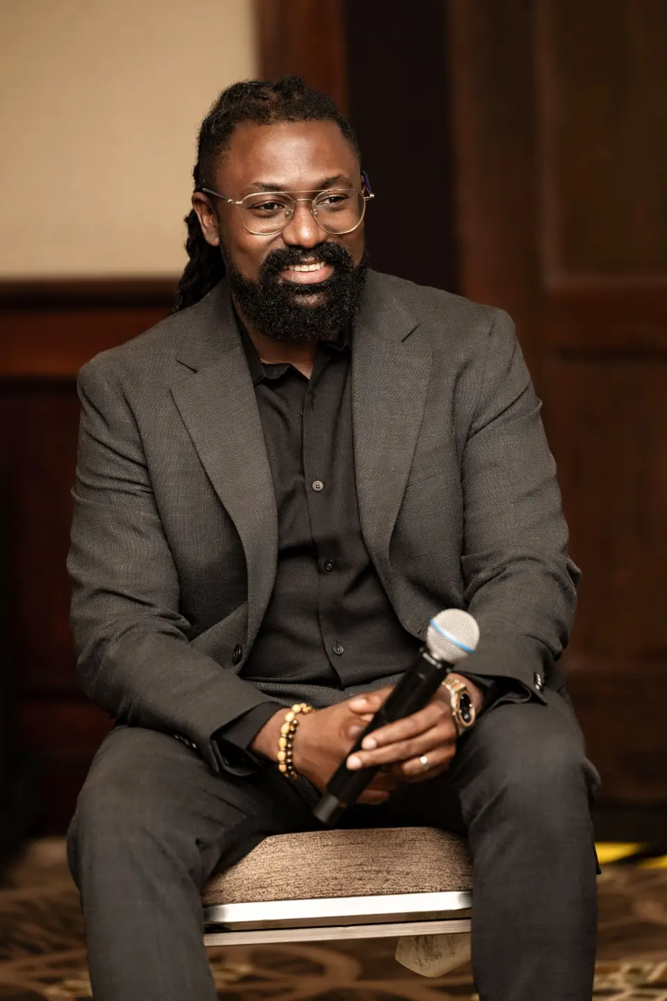 Chinedum Ucheoma seated and holding a microphone