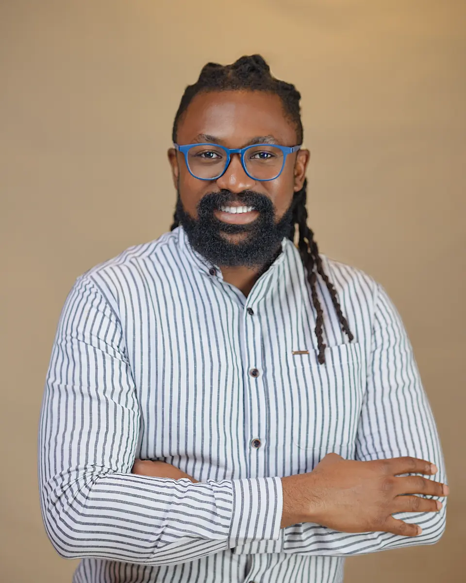 Chinedum Ucheoma smiling in a striped shirt and blue glasses